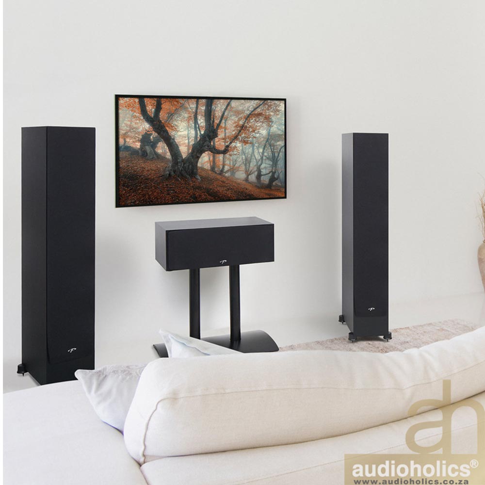 Paradigm-SE3000 - Audioholics South Africa Modern living room with a pair of tall black floor speakers, a center speaker on a stand, a wall-mounted TV showing a forest scene, and a white sofa in the foreground.