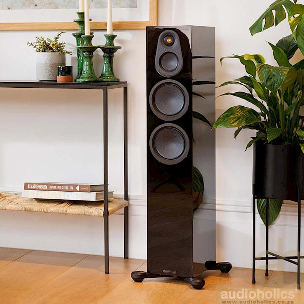 Monitor-Audio-Silver-300-Main - Audioholics South Africa Tall black floor-standing speaker with three drivers in a modern living room beside a console table and green plants