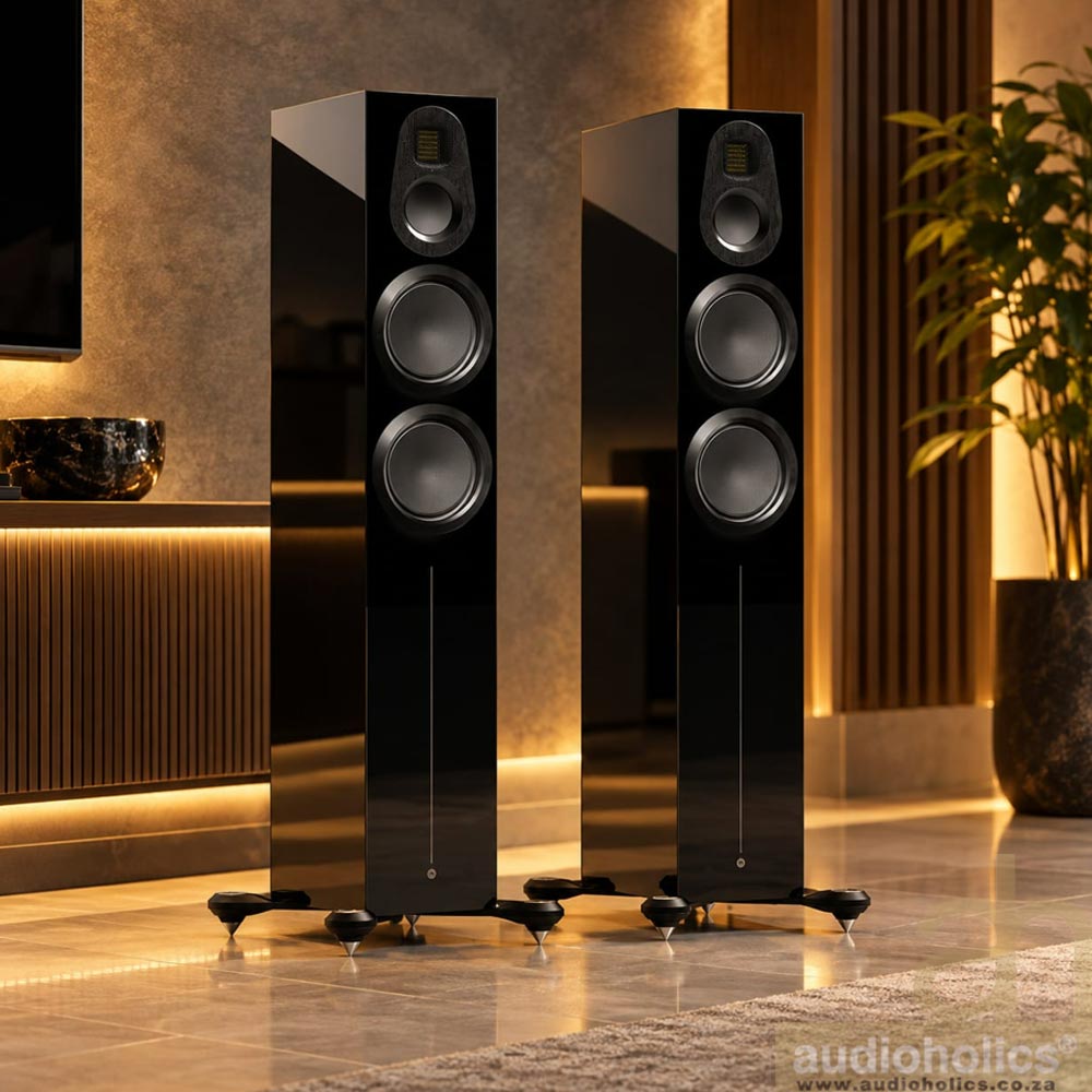Monitor-Audio-Gold-300-Trade-In - Audioholics South Africa Two tall black floor-standing speakers in a modern, warmly lit living room.